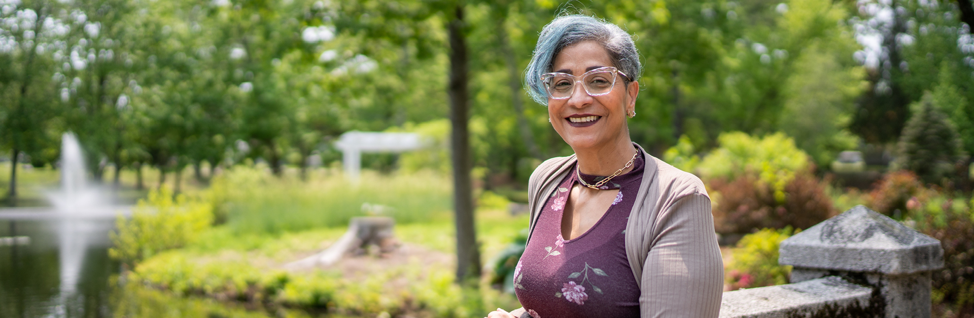 A woman standing on a stone bridge in a park with a pond