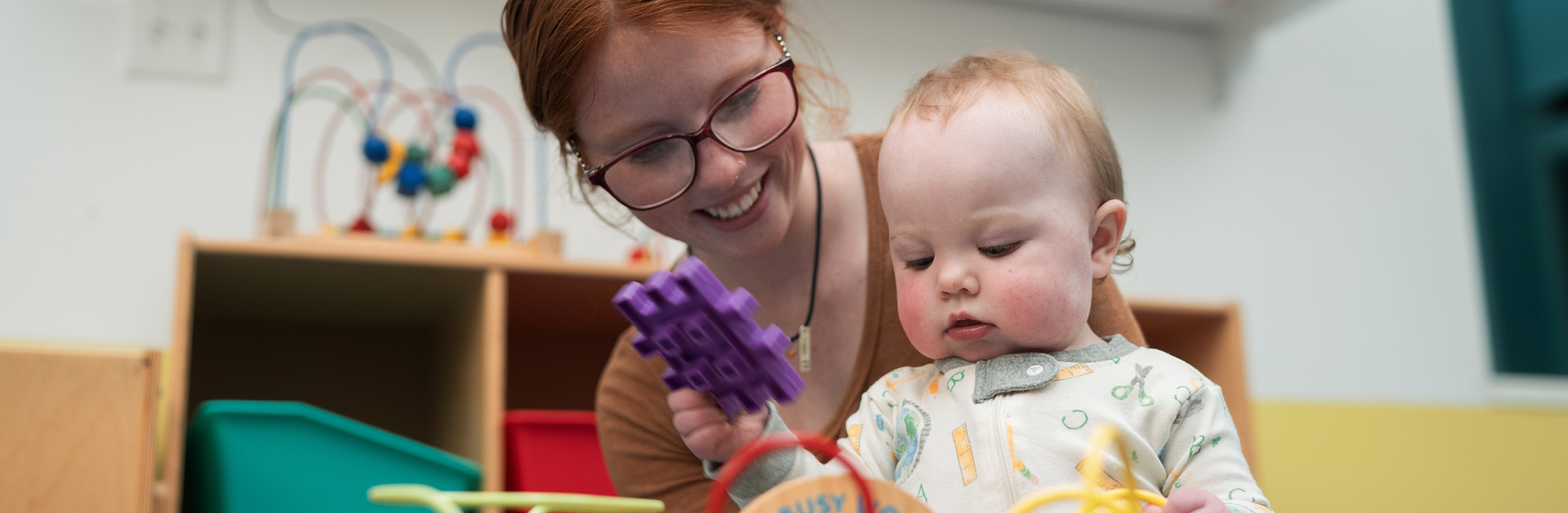 a young woman wearing glasses playing with a baby