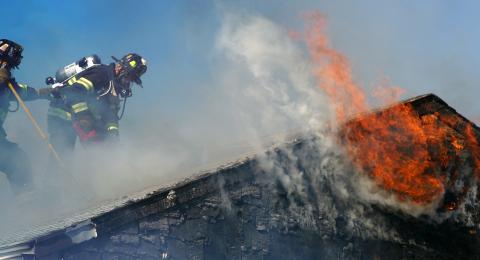 Two firefighters on top of a burning roof