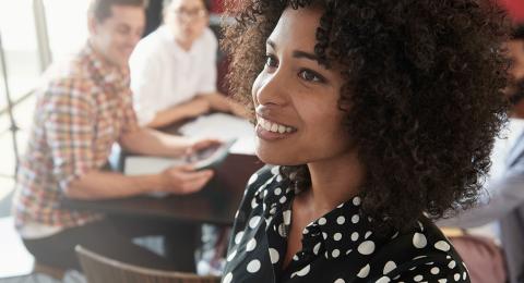 Young professional with curly hair and a flowered print shirt giving a roundtable presentation