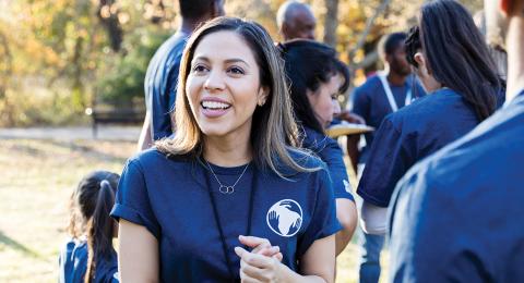 Smiling person in an event shirt surrounded by other event organizers outdoors