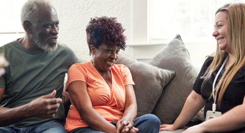 An older couple speaking with a female counselor in their home