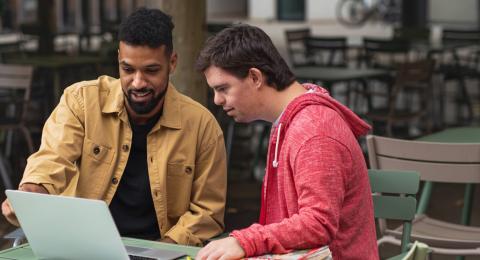 a man helping a teen with schoolwork on a laptop 