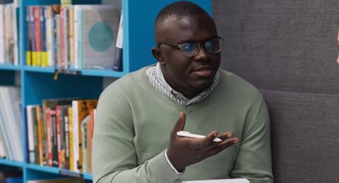 A male therapist talking to a young girl in college library and holding clipboard