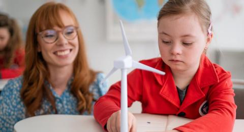 A paraprofessional watches a young student work on a science project