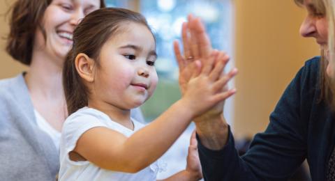 A young girl give adult woman a high-five in a health and wellness office