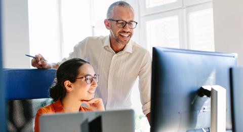 a man and woman working together at a computer in an office