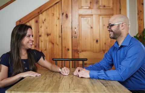 a man and woman sitting across from a table smiling at each other