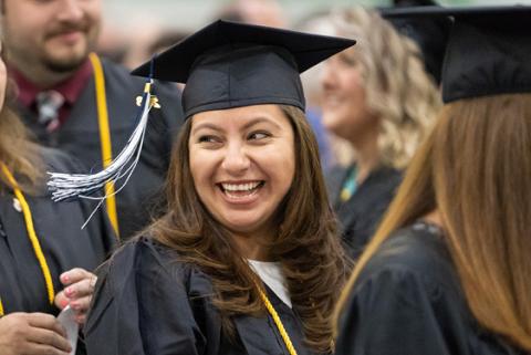 Proud and smiling student at commencement wearing a graduation gown and mortarboard