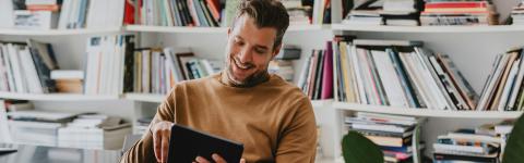 Man with tablet and bookshelf