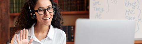 Teacher with headset and laptop waving