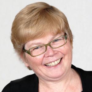 headshot of a middle aged blonde woman with short hair and glasses