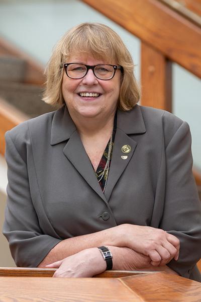 headshot of a middle aged blonde woman with glasses in a blazer