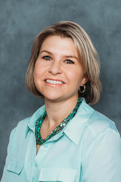 headshot of a blonde woman wearing a blue blouse