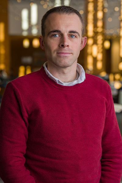 headshot of a man wearing a red sweater