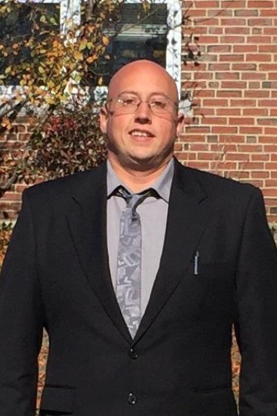 photo of a man standing in a suit outside